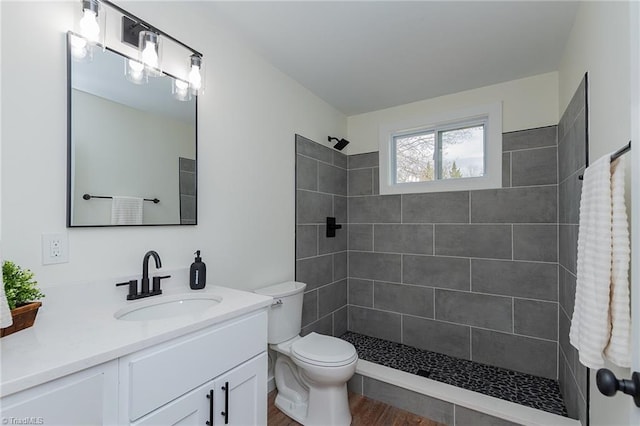 bathroom with tiled shower, toilet, and vanity