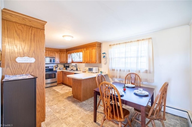 kitchen with stainless steel appliances, a peninsula, a sink, light countertops, and brown cabinets