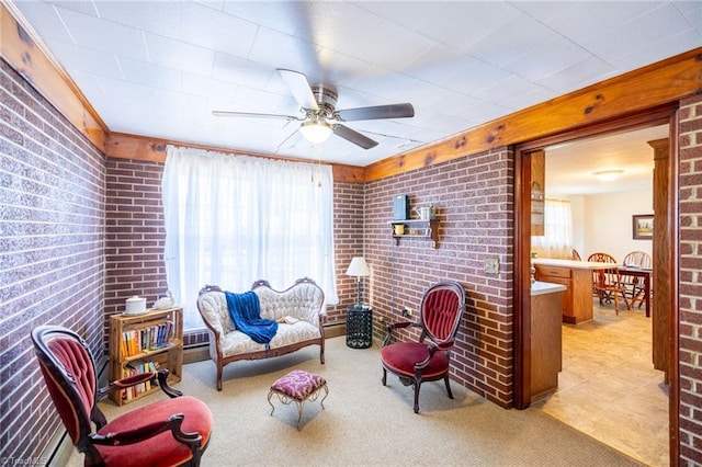 living area featuring brick wall, ceiling fan, and light colored carpet