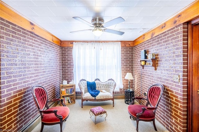 sitting room featuring brick wall, a ceiling fan, and carpet flooring