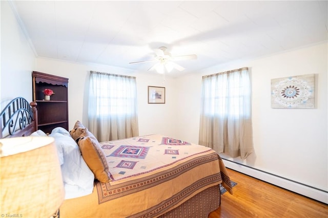 bedroom with ornamental molding, a baseboard radiator, a ceiling fan, and wood finished floors