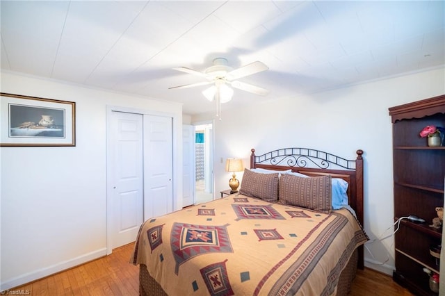 bedroom featuring ceiling fan, a closet, baseboards, and wood finished floors