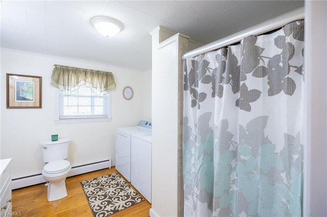 bathroom featuring toilet, independent washer and dryer, baseboard heating, and wood finished floors