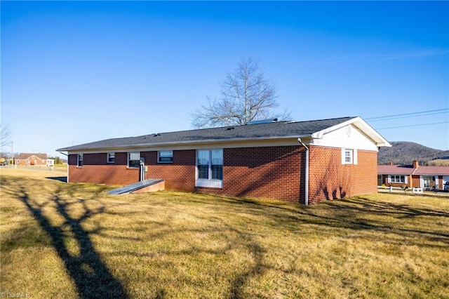 back of property with a yard and brick siding