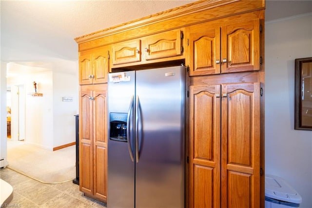 kitchen with brown cabinets, stainless steel fridge, and baseboards