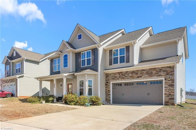 view of front facade with an attached garage, covered porch, stone siding, and driveway