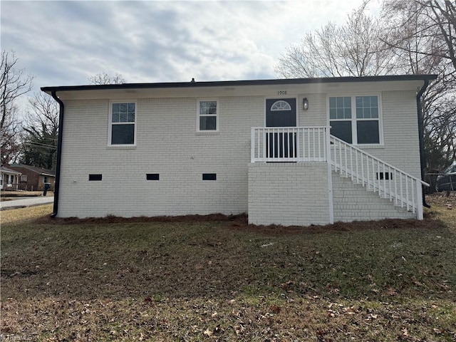 view of front of home featuring stairs, brick siding, crawl space, and a front yard