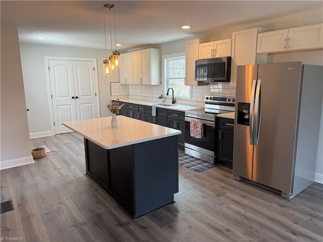 kitchen featuring dark wood-type flooring, stainless steel appliances, a sink, and light countertops