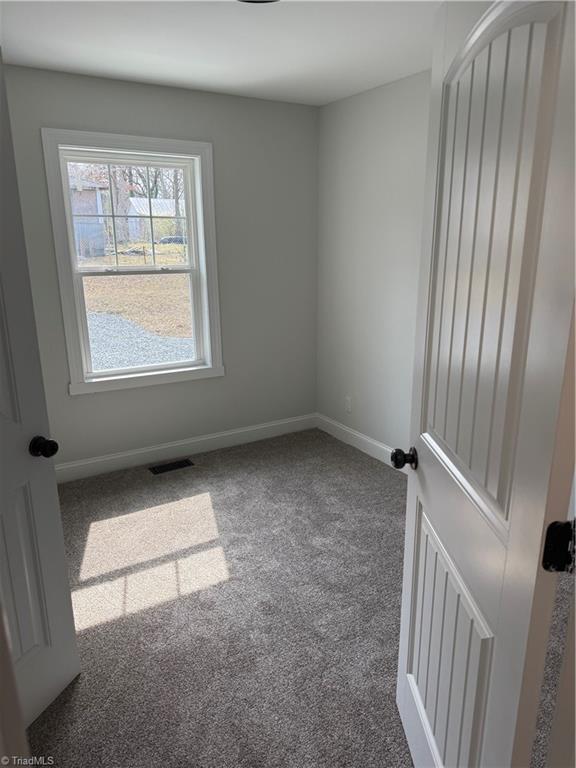 carpeted spare room with visible vents and baseboards