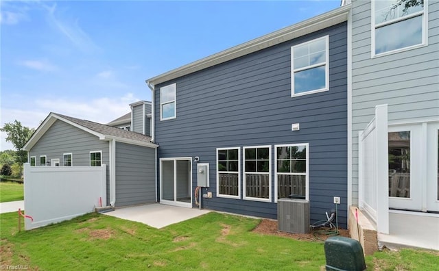 rear view of property with a lawn, cooling unit, and a patio