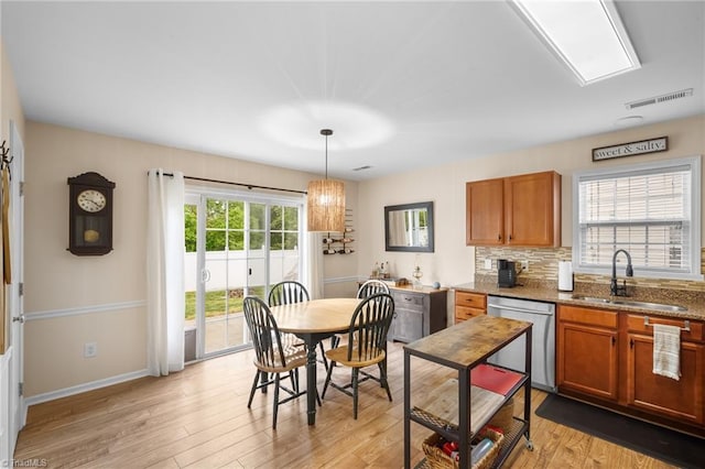 kitchen with brown cabinets, dishwasher, light wood finished floors, and a sink