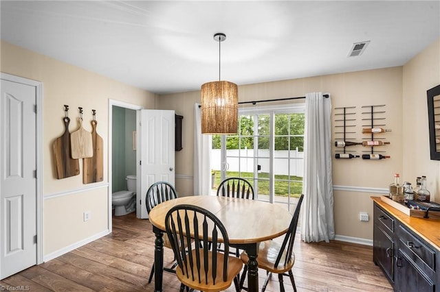 dining area with baseboards, visible vents, and light wood finished floors