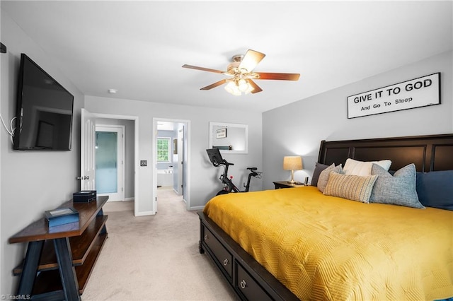 bedroom with ensuite bathroom, ceiling fan, light carpet, and baseboards