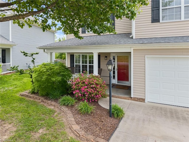 entrance to property featuring a lawn, a shingled roof, and covered porch