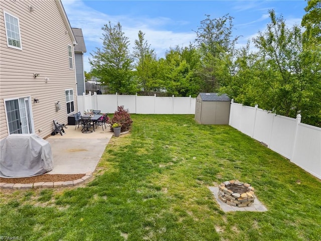 view of yard featuring a fire pit, a patio, a storage unit, an outbuilding, and a fenced backyard