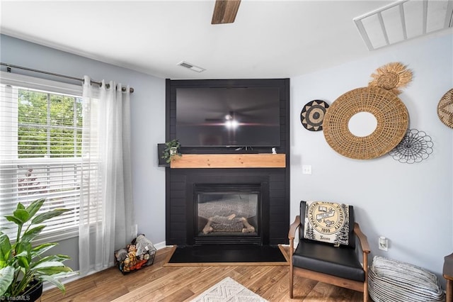 living area with visible vents, wood finished floors, and a fireplace