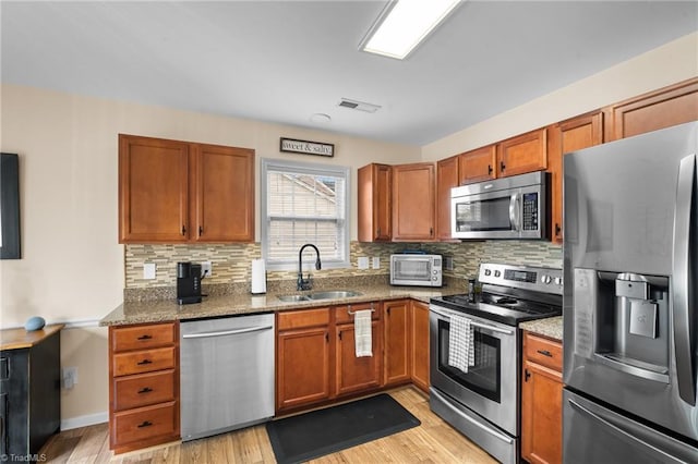 kitchen featuring visible vents, stainless steel appliances, stone countertops, and a sink