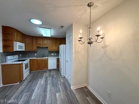 kitchen with dark wood-style flooring, open shelves, a notable chandelier, a sink, and white appliances