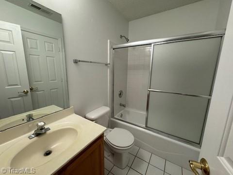 full bathroom featuring tile patterned flooring, vanity, toilet, combined bath / shower with glass door, and visible vents