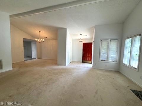 unfurnished living room with an inviting chandelier, baseboards, vaulted ceiling, and carpet flooring