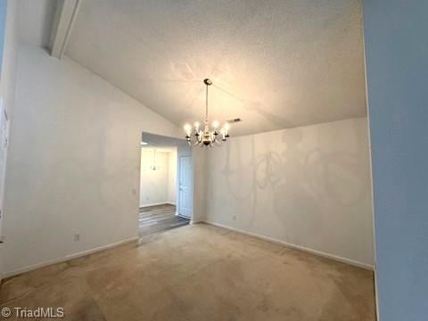 unfurnished dining area featuring an inviting chandelier, carpet floors, baseboards, and vaulted ceiling