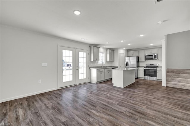 kitchen with appliances with stainless steel finishes, french doors, dark wood-type flooring, sink, and a center island