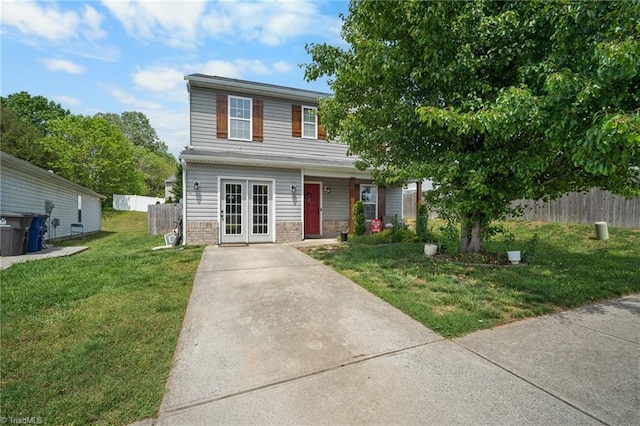 traditional-style house featuring fence, french doors, a front yard, and concrete driveway