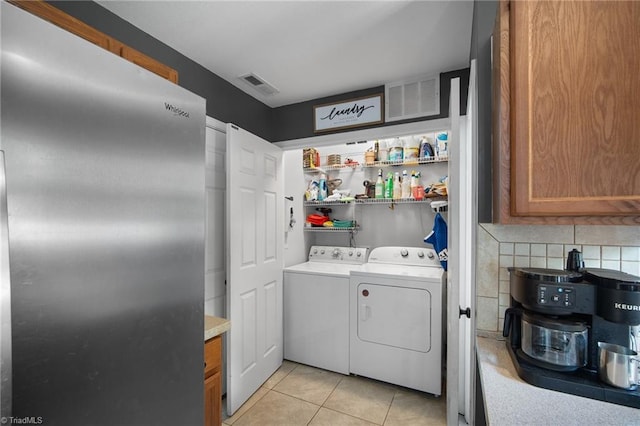 laundry area featuring washer and dryer, light tile patterned flooring, laundry area, and visible vents
