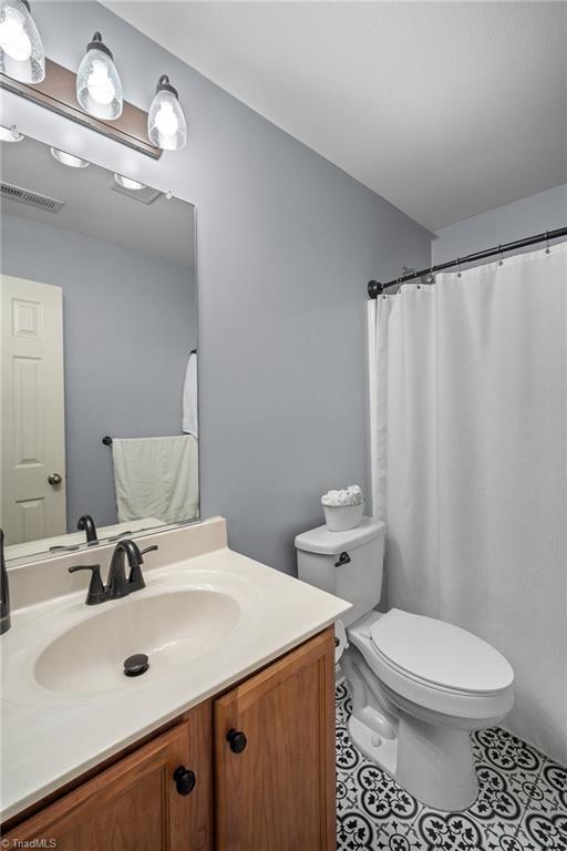 bathroom with toilet, tile patterned floors, visible vents, and vanity