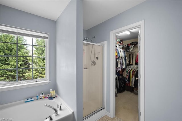 bathroom featuring a shower stall, a garden tub, and a spacious closet