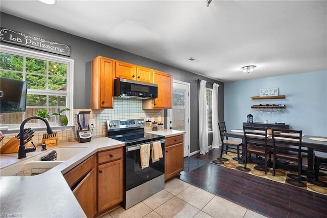 kitchen with electric range, visible vents, tasteful backsplash, a sink, and light countertops
