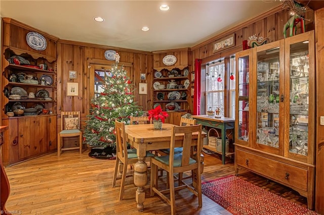 dining room featuring crown molding, light hardwood / wood-style floors, and wood walls