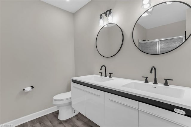 full bath featuring double vanity, wood finished floors, a sink, and toilet