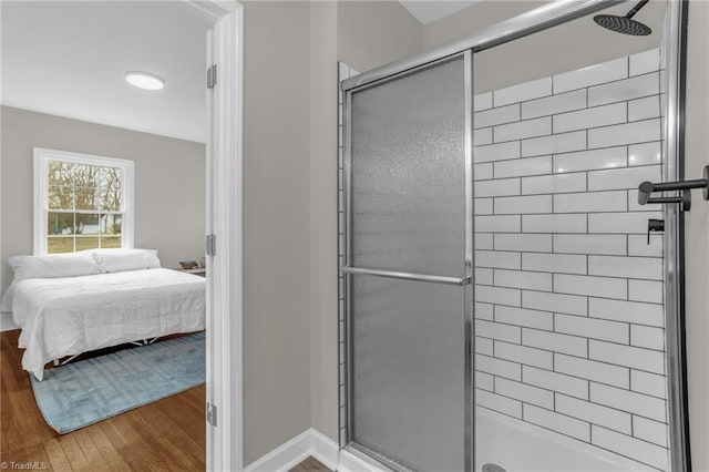 ensuite bathroom featuring ensuite bathroom, a stall shower, wood finished floors, and baseboards