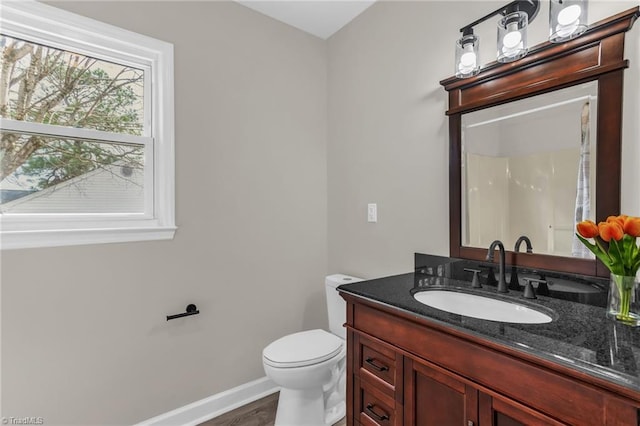 bathroom with baseboards, vanity, toilet, and wood finished floors