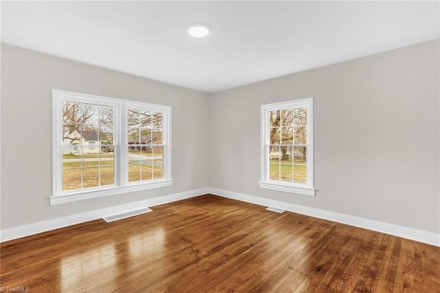 unfurnished room with visible vents, baseboards, and wood finished floors