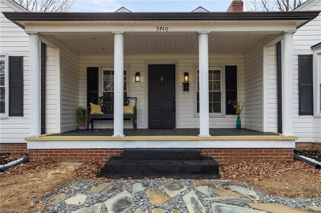 entrance to property with covered porch and a chimney