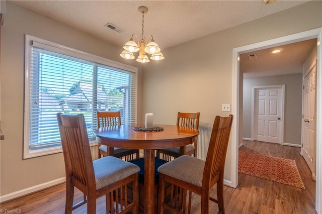 dining space featuring hardwood / wood-style flooring, a textured ceiling, and an inviting chandelier