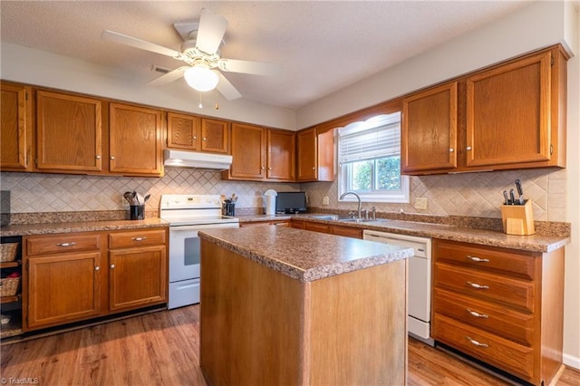 136 Fairway Dr, Bermuda Run, NC 27006 - kitchen featuring white appliances, under cabinet range hood, light wood finished floors, brown cabinets, and backsplash