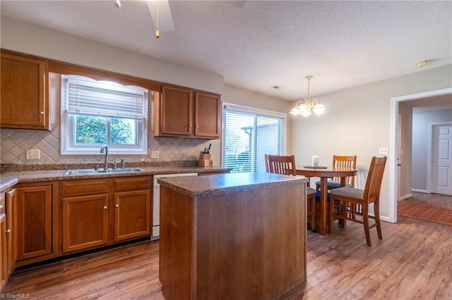 136 Fairway Dr, Bermuda Run, NC 27006 - kitchen featuring dishwashing machine, light wood-style floors, decorative backsplash, brown cabinetry, and a kitchen island