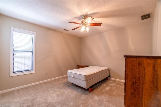 bedroom featuring a textured ceiling, light colored carpet, and ceiling fan