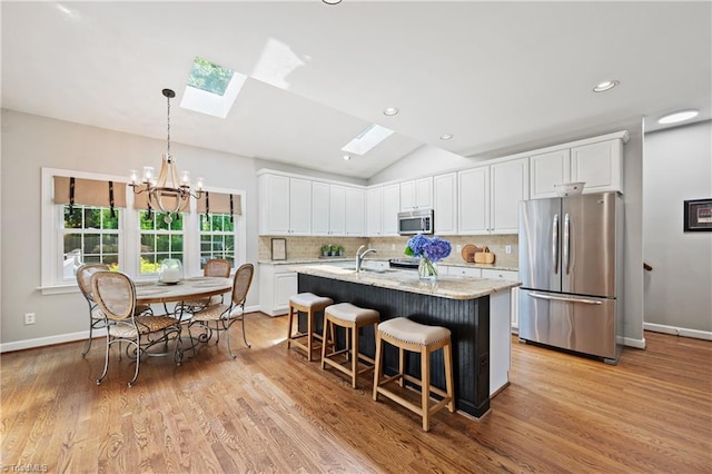 4919 Setter Ct, Jamestown, NC 27282 - kitchen with stainless steel appliances, a skylight, a chandelier, white cabinets, and tasteful backsplash