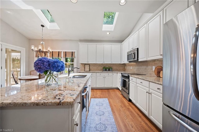 4919 Setter Ct, Jamestown, NC 27282 - kitchen featuring stainless steel appliances, a skylight, a sink, lofted ceiling, and white cabinets