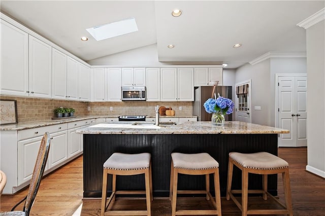 4919 Setter Ct, Jamestown, NC 27282 - kitchen featuring stainless steel appliances, a skylight, a breakfast bar area, white cabinetry, and tasteful backsplash