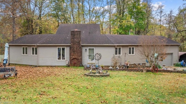 rear view of property with a garage and a yard