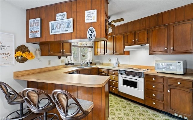 kitchen with sink, a breakfast bar, kitchen peninsula, ceiling fan, and white appliances