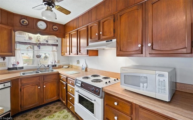 kitchen with a textured ceiling, sink, white appliances, and ceiling fan