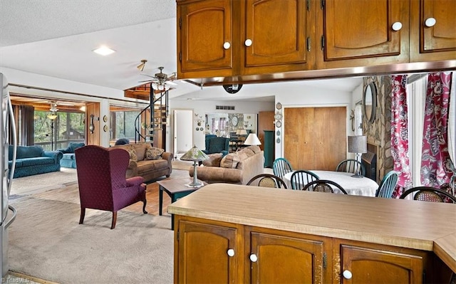 kitchen with a textured ceiling, lofted ceiling, ceiling fan, and light carpet