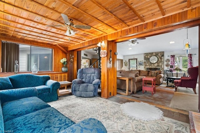 living room featuring wood walls, ceiling fan, hardwood / wood-style floors, a stone fireplace, and wood ceiling