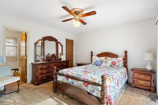 bedroom with light colored carpet, ceiling fan, and ensuite bath